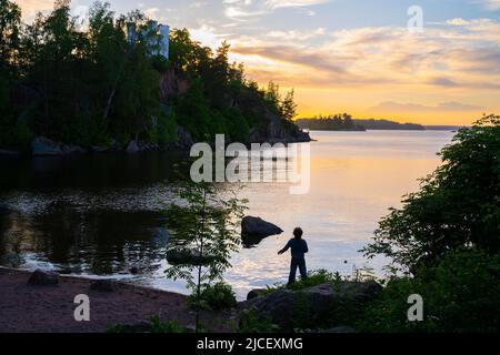 Silhouette di una bambina sulla riva del Golfo di Finlandia nel Parco MonRepo vicino a Vyborg, Russia. Foto di alta qualità Foto Stock