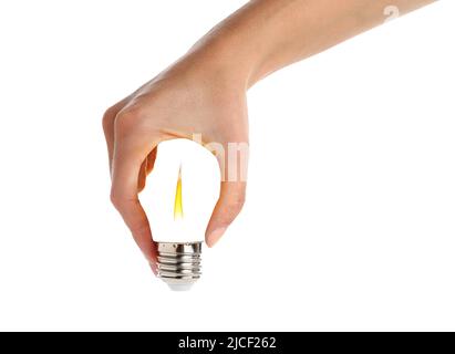 Mano che tiene una lampadina. La fiamma che brucia all'interno della lampadina. La mano femmina contiene una lampadina a risparmio energetico, isolata su sfondo bianco. Manipolazione delle foto.