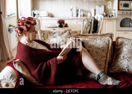 Vecchia donna attiva anziana con rulli in capelli si prendono cura di se stessa nel suo fine settimana. Fate attenzione alla pelle invecchiata, coccolandosi Foto Stock