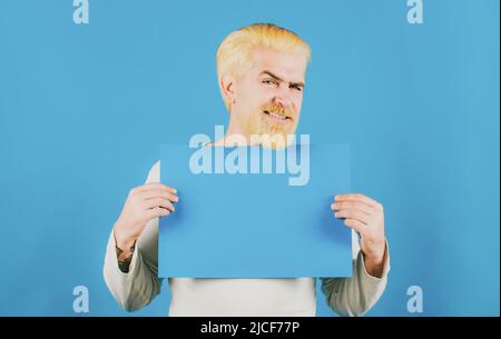 Ritratto dell'uomo che mostra un cartello blu vuoto con spazio di copia per slogan o testo. Il giovane mostra un foglio di carta nella macchina fotografica su un colore Foto Stock