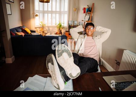 Uomo asiatico rilassato alla scrivania Foto Stock