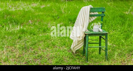 Decorazione con una vecchia sedia e una caffettiera in un giardino naturale Foto Stock