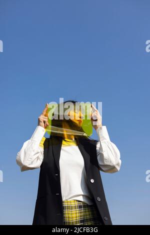 Donna che guarda sul lato dietro il foglio giallo Foto Stock