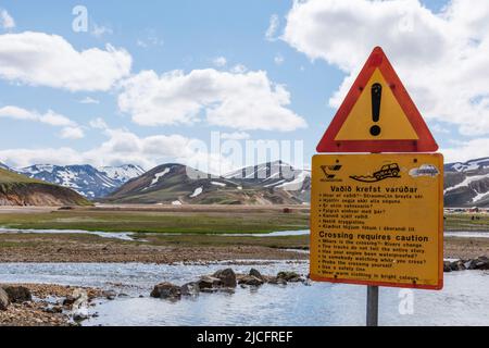 Il sentiero escursionistico di Laugavegur è il più famoso tour di trekking di più giorni in Islanda. Paesaggio girato dalla zona intorno a Landmannalaugar, punto di partenza del sentiero escursionistico a lunga distanza negli altopiani dell'Islanda. Cartello di avvertenza "l'attraversamento richiede attenzione Foto Stock