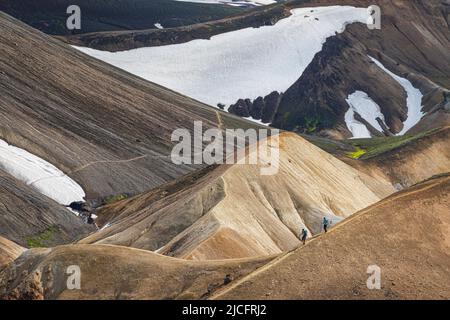 Il sentiero escursionistico di Laugavegur è il più famoso tour di trekking di più giorni in Islanda. Paesaggio girato dalla zona intorno a Landmannalaugar, punto di partenza del sentiero escursionistico a lunga distanza negli altopiani dell'Islanda. Due escursionisti che camminano sul sentiero. Foto Stock