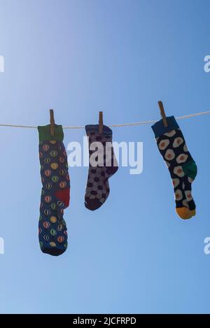 Calze solitario diverso senza partner su una linea di abbigliamento, immagine simbolo 'Lost Socks Memorial Day'. Foto Stock