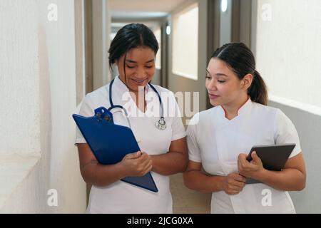 Latino Femminile medici parlare mentre si cammina in ospedale Foto Stock