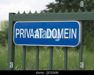 Targa blu con lettere bianche su una recinzione che dice dominio privato in olandese Foto Stock