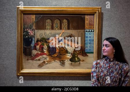 Londra, Regno Unito. 13 giugno 2022. Un membro dello staff vede "i musichi a riposo", di Rudolf Ernst (Est. £100.000-150.000) in anteprima di Bonhams Orientalist art sale. L'asta si svolgerà il 14 giugno presso le gallerie Bonhams New Bond Street. Credit: Stephen Chung / Alamy Live News Foto Stock