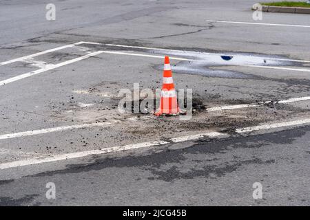 segnalare il cono di traffico su una botola fognaria difettosa su un'autostrada urbana Foto Stock