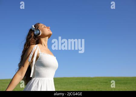 Donna meditante con cuffie wireless in un campo verde Foto Stock