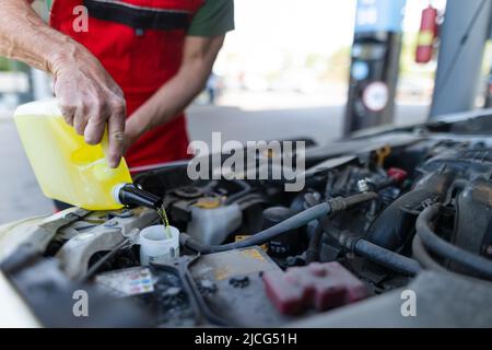 Il meccanico dell'automobile sostituisce e versa l'olio nel motore alla stazione di servizio di riparazione di manutenzione Foto Stock