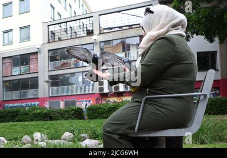 La vita quotidiana nel centro di Norrköping, Svezia, lunedì. Una donna nutre piccioni in un parco nel centro della città. Foto Stock