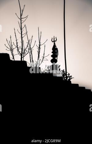 Una silhouette di un tempio Shiva con un tridente o un trishul sulla parte superiore. Uttarakhand India. Foto Stock