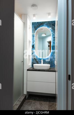 Interni in bagno contemporanei con specchio luminoso e tavolo lavabo Foto Stock