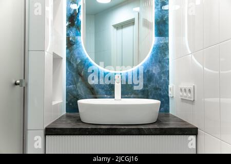 Interni in bagno contemporanei con specchio luminoso e tavolo lavabo Foto Stock