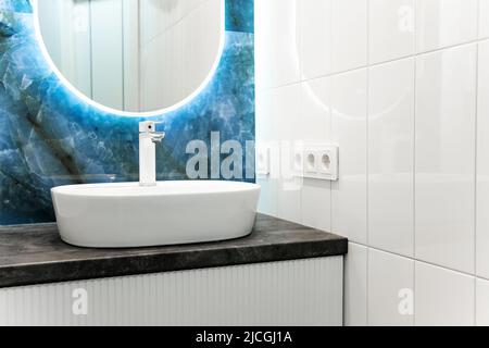 Interni in bagno contemporanei con specchio luminoso e tavolo lavabo Foto Stock