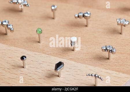 Bella gioielli piercing su display in legno. Scatto macro. Messa a fuoco selettiva Foto Stock