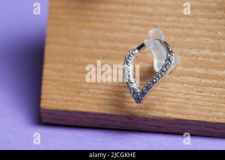 Bella gioielli piercing su display in legno. Scatto macro. Messa a fuoco selettiva Foto Stock