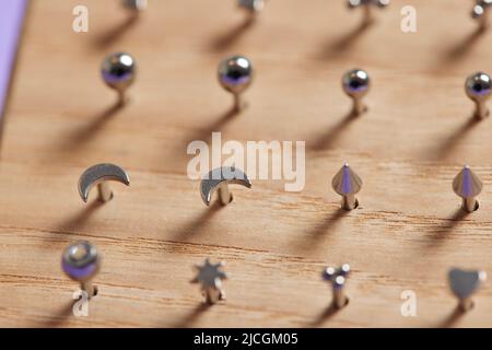 Bella gioielli piercing su display in legno. Scatto macro. Messa a fuoco selettiva Foto Stock