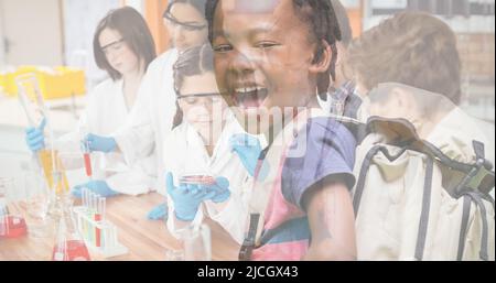 Scolaro afroamericano con studenti a bocca aperta e multirazziale che fanno esperimenti in laboratorio Foto Stock