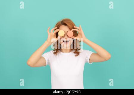 divertente ragazza tenere dolce macaron biscotto francese su sfondo blu Foto Stock