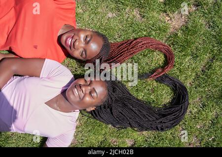 due donne afroamericane che si stendono a forma di cuore con le loro trecce Foto Stock