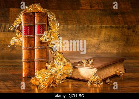 Vecchi libri e oro foglia su sfondo di legno, concetto di educazione costosa Foto Stock