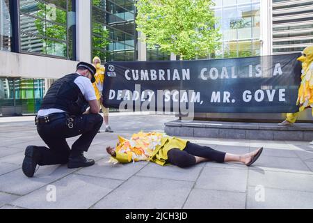 Londra, Regno Unito. 13th giugno 2022. Un poliziotto parla con un manifestante che si trova sul terreno. Gli attivisti della ribellione dell'estinzione vestiti come canari hanno organizzato una protesta contro la miniera di carbone Cumbria fuori dall'ufficio domestico. Credit: Vuk Valcic/Alamy Live News Foto Stock