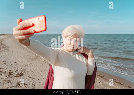 Signora sicura che prende selfie sulla spiaggia Foto Stock