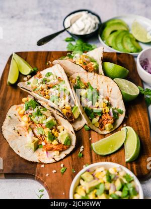 Alto angolo di tacos morbidi con pollo, mais, avocado e lime. Foto Stock