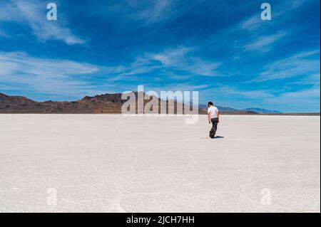 Un ragazzo in piedi sulle saline in una luminosa giornata di sole nello Utah Foto Stock