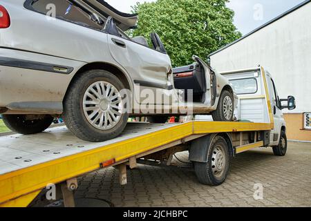 Carico di un'auto distrutta su un autocarro trainato dopo un incidente stradale, concetto di guida pericolosa dopo aver bevuto alcol, concetto di assistenza stradale Foto Stock