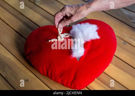 primo piano delle donne più anziane che prendono a mano gioielli da un cuore rippato ripieno Foto Stock