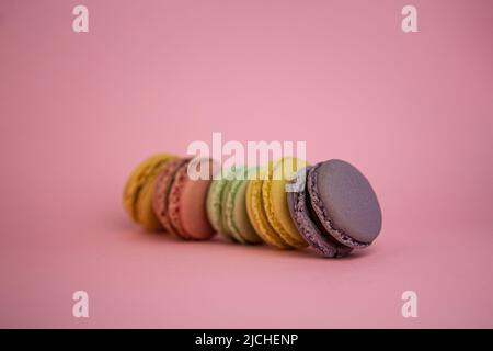 Maccheroni francesi assortiti allineati su sfondo rosa con spazio copia Foto Stock