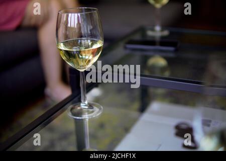 un bicchiere di champagne su un tavolo di vetro in un'atmosfera informale Foto Stock