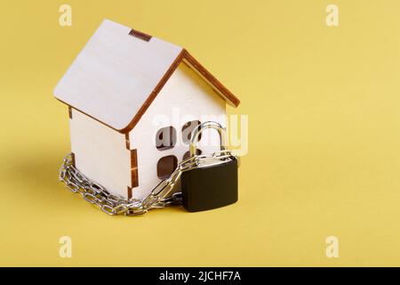 Arresto dell'alloggiamento. Casa del castello. Piccola casa giocattolo e una catena con un lucchetto. Sfratto per mancato pagamento. La porta chiusa a chiave della casa. Foto Stock