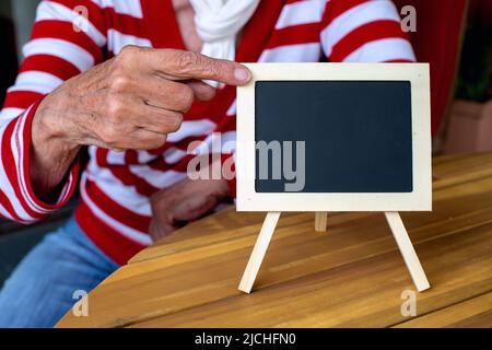 primo piano di una mano di donne più anziane che punta ad una lavagna Foto Stock