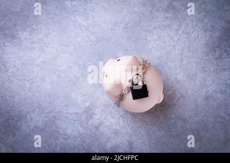Chiudiosassata. Risparmio bloccato. La banca del piggy è legata con una catena e bloccata. Concetto di protezione dei soldi. Foto Stock