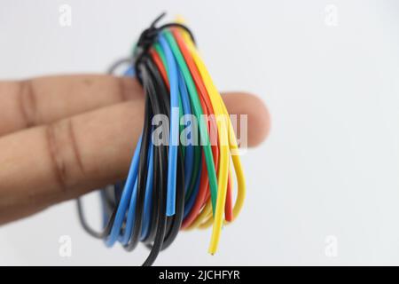 I fili di colore diverso per i collegamenti dei componenti elettronici sono tenuti in mano su sfondo bianco Foto Stock