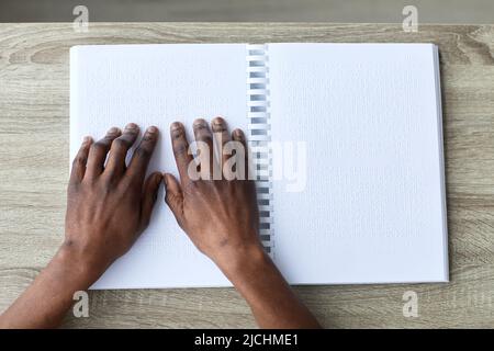 Minimal top view closeup di uomo cieco lettura libro in braille, accessibile istruzione concetto, spazio copia Foto Stock