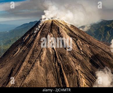 Mentre ci avviciniamo dall'aria, il vulcano Bagana in Papua Nuova Guinea emette nuvole di fumo Foto Stock