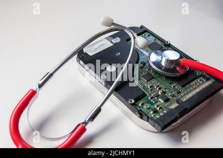 Lo stetoscopio rosso con unità disco rigido interna hdd contiene record di stato e dati paziente sensibili con controllo medico hardware e violazione dei dati di riposo Foto Stock