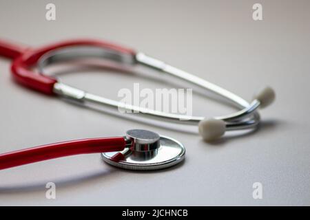 Stetoscopio rosso presso l'ufficio medico per il controllo cardio professionale e il controllo del battito cardiaco sano da parte del cardiologo in sala di trattamento clinico Foto Stock