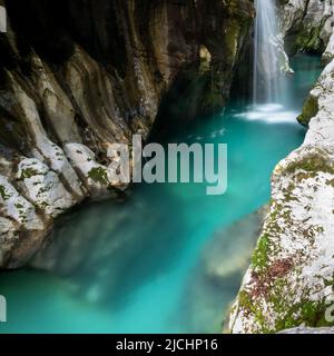 Immagine sfocata di una bella cascata che cade in un bel fiume di soca smeraldo che scorre attraverso una grande gola. Foto Stock