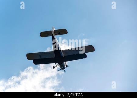 Piccolo biplano che vola contro il cielo blu Foto Stock