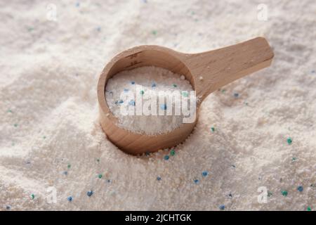 Da sopra di misurino di legno con detersivo per bucato messo su pila di polvere bianca pulita di lavaggio in camera luminosa Foto Stock