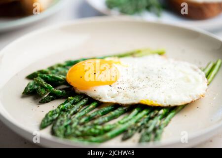 Uova fritte con asparagi verdi. Idee per il pranzo veloce, colazione sana, cibo estivo. Foto Stock