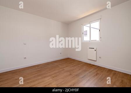 Camera vuota in appartamento ristrutturato con pareti dipinte di bianco, pavimenti in parquet di quercia e legno di quercia e finestra in alluminio con pannelli scorrevoli ed elettrici Foto Stock