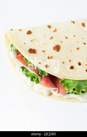 L'appartamento italiano Street food si trova con piadina isolata su uno sfondo bianco. Piadina romagnola - piatto italiano con prosciutto, insalata e crema di latte Foto Stock